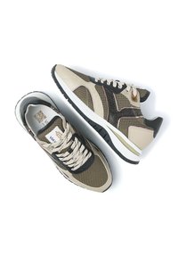 Beige und schwarze Sneakers mit Mesh-Einsätzen, strukturierten Akzenten, weißer Sohle und Schnürsenkeln; mit QR-Code-Etikett im Inneren eines Schuhs.