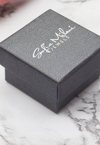 Scatola per gioielli nera e testurizzata con coperchio a cerniera, con un logo argentato che recita 'Sophie Milani Jewels' sulla parte superiore.