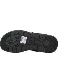 Suela de zapatilla negra con una superficie de goma texturizada, que presenta un patrón de dibujo geométrico para un mejor agarre y una etiqueta del fabricante adjunta.