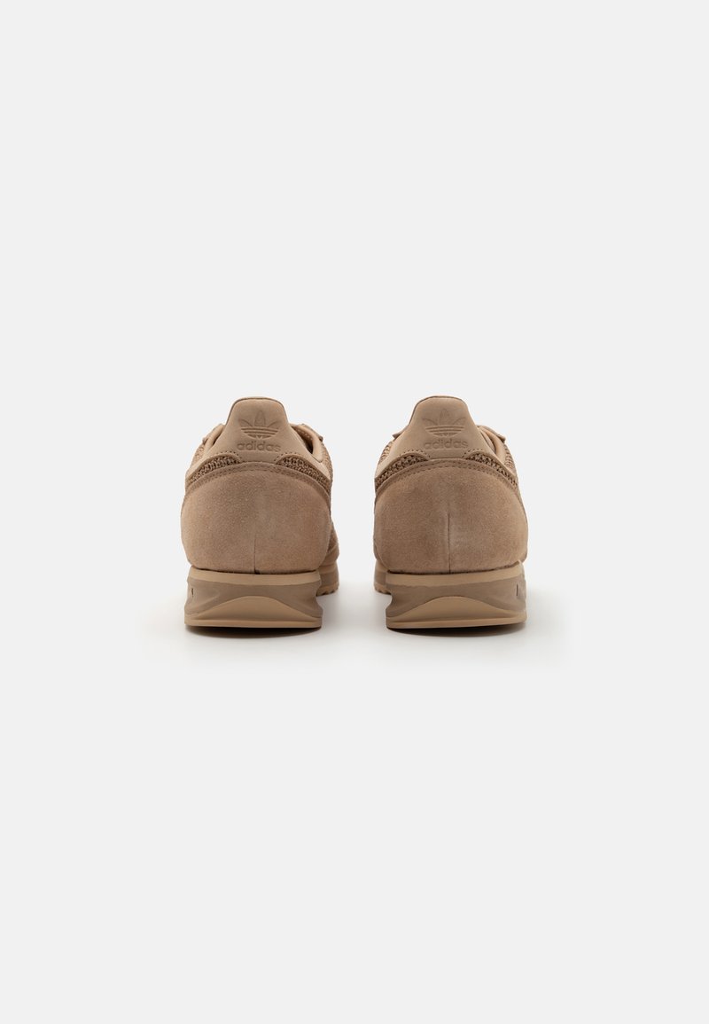 Zapatillas atléticas de ante marrón con detalles texturizados, diseño de perfil bajo y puntera redondeada. Cuentan con un cuello acolchado y suela de goma.
