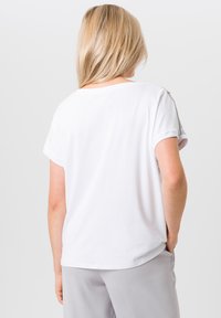 Witte T-shirt met korte mouwen, in een relaxte pasvorm, ronde halslijn en opgerolde mouwen, gemaakt van zachte stof. Achteraanzicht toont een gladde textuur.