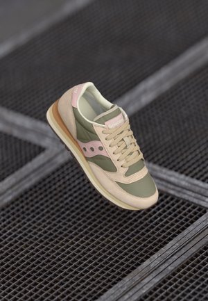 Beige and green sneaker with suede and leather panels, rounded toe, lace-up closure, pink branding, and textured rubber sole.