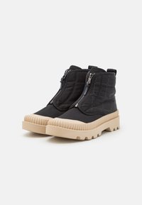 Stivaletti neri trapuntati alla caviglia con zip laterali e suola in gomma beige spessa, caratterizzati da un design testurizzato e una suola robusta.