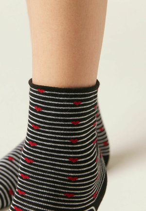 Černobílé pruhované kotníkové ponožky s červenými srdíčky, měkká tkanina, elastický lem, těsný střih a hladká textura.
