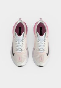 Ζευγάρι λευκά και ροζ παπούτσια τρεξίματος Nike με μαύρα λογότυπα swoosh, φαίνονται από πάνω σε λευκό φόντο.