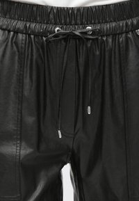 Mustad kunstnahast lühikesed püksid elastse vöökohaga, nööriga kinnitamine ja hõbedased detailid. Omavad küljetaskuid ja siledat tekstuuri.