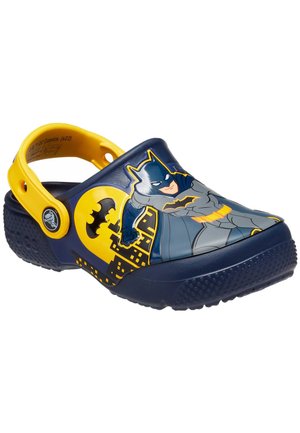 Sabots Batman fabriqués en plastique durable, avec un corps bleu marine, des accents jaunes et un graphique de Batman avec une skyline de la ville.