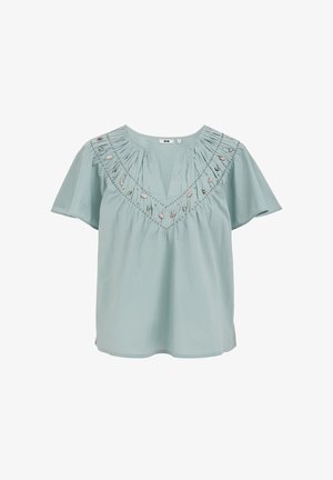 Hele sinine lühikeste varrukatega pluus V-kaelusega, volditud kaelusega ja tikitud lillemustriga joont mööda.