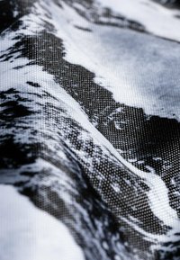 Abstrakter Druckstoff mit einer strukturierten Oberfläche und einem monochromen Design aus Wellen und Mustern in Schwarz und Weiß.