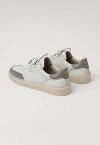 Sneakers bianchi in pelle con punta e tallone in suede grigio. Forma arrotondata con tomaia texture e lacci piatti. Suola di colore chiaro.