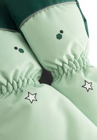 Mintgrüne Handschuhe mit elastischen Bündchen, die schwarz-grüne sechseckige Muster und weiße Sternelemente im Handbereich aufweisen.