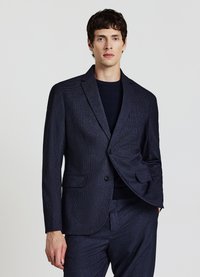 Marineblauer Textur-Blazer mit Zwei-Knopf-Verschluss, aufgeschlagenen Revers und zwei Seitentaschen. Trägt man über einem dunklen Pullover.