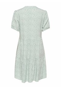 Robe courte à manches courtes vert clair avec motif de feuilles blanches, taille froncée et jupe à volants, vue de dos sur fond blanc.
