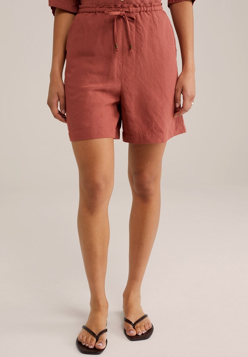 Lněné šortky v rezavé barvě s elastickým pasem a šňůrkou, s volným střihem a bočními kapsami. Texturovaná látka. Ploché sandály.