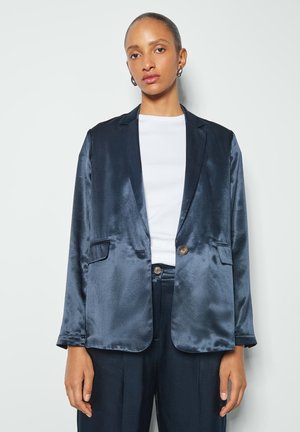 Marineblauer Satinblazer mit glatter Textur, zwei vorderen Taschen, einem Einzelknopfverschluss und Reverskragen, kombiniert mit einem weißen Oberteil.