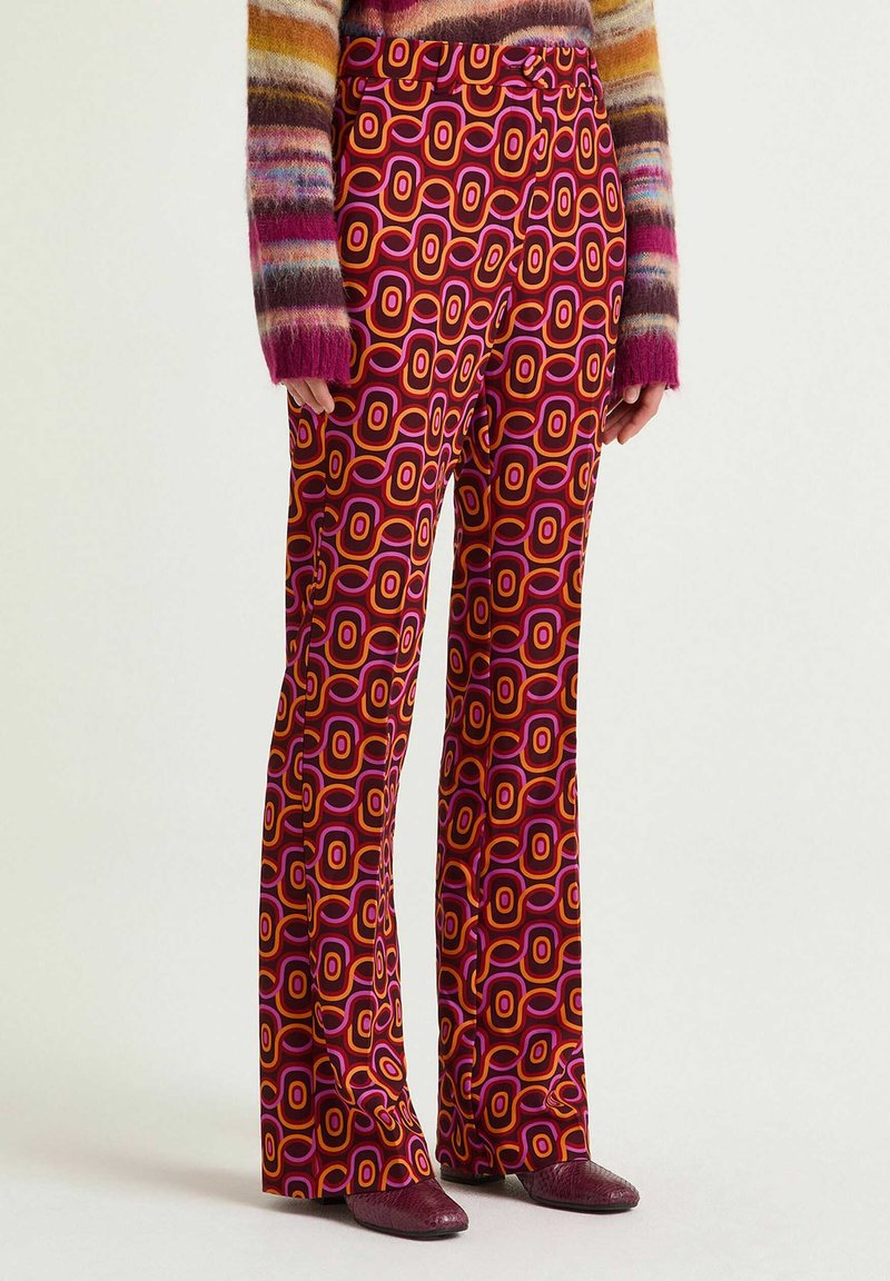 Pantalon évasé avec un motif géométrique audacieux en rose, orange et bordeaux. Confectionné dans un matériau lisse avec une taille cintrée et des poches latérales.