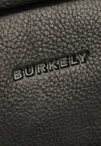 Black leather material features a textured surface with a subtle grain. The brand name "BURKELY" is embossed prominently.