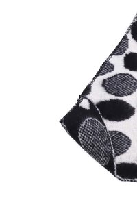 Coperta a scacchi in bianco e nero con grandi forme circolari. Il tessuto presenta una texture morbida e un bordo cucito ben visibile.