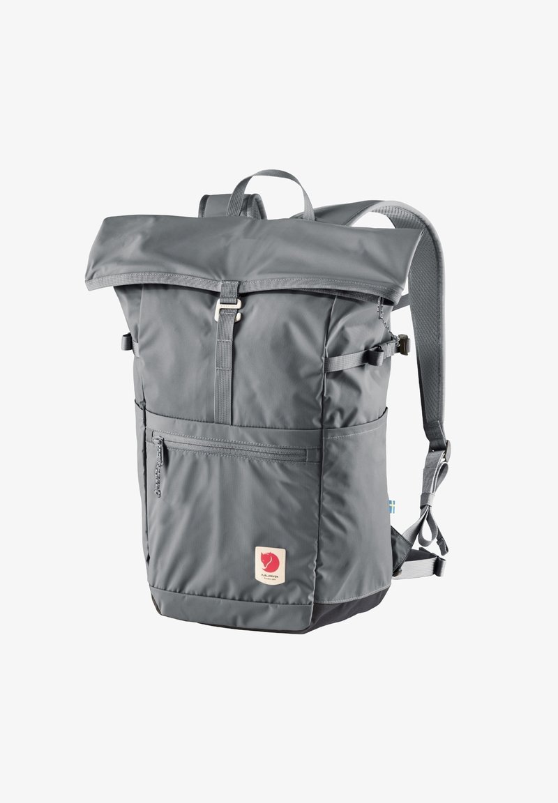 Sac à dos gris à rabat supérieur avec une poche zippée à l'avant, des bretelles réglables et un patch logo ; fabriqué en nylon durable et texturé.