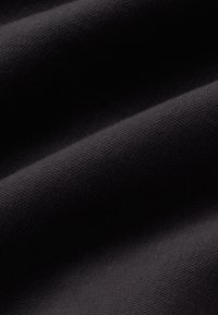 Sort stof med en glat tekstur, der viser subtil ribbning. Materialet ser let og let elasticitet ud med ensartet farvefordeling.