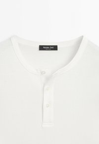 White short-sleeve shirt with round neckline and three button placket, featuring a Massimo Dutti label at the collar.