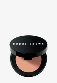 Blush Bobbi Brown dans un boîtier rond. Coque extérieure noire brillante avec logo blanc ; l'intérieur présente une poudre douce de couleur rose clair.