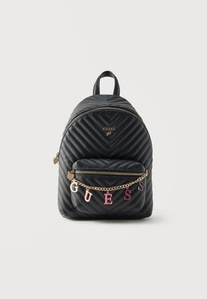 Sac à dos matelassé noir avec poche zippée à l'avant, chaîne dorée et breloques lettres multicolores formant « GUESS », et poignée supérieure.