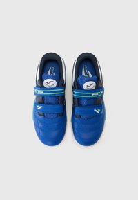 Zapatillas sintéticas azules con acentos en marino, que cuentan con correas de Velcro, perforaciones y una franja verde. Incluye un logo circular de la marca en la lengüeta.