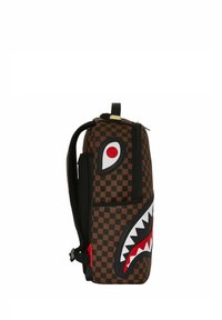 Zaino a scacchi marrone con un grande design di squalo e accenti rossi e bianchi. Progettato con cerniere e cinturini laterali per una maggiore funzionalità.