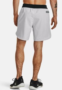 Hellgraue Sportshorts mit schwarzem Bund, die perforierte Details nahe dem Saum und eine kleine Seitentasche aufweisen.
