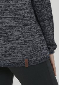 Pull en tricot bleu marine foncé et gris avec un motif texturé. Doté d'une étiquette en cuir marron avec "OXIMO" à l'ourlet. Coupe confortable et décontractée.