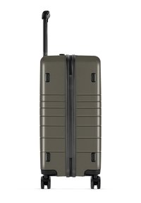 Hartschalentrolley in olivgrün mit strukturierten Oberflächen, doppeltem Reißverschluss und einem ausziehbaren schwarzen Griff. Mit vier Rädern für einfache Mobilität.