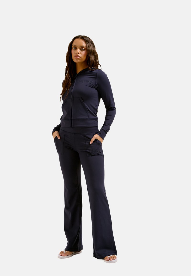 Marineblauer Reißverschluss-Hoodie mit gerippten Bündchen und zwei vorderen Taschen, kombiniert mit passenden hoch taillierten Schlaghosen mit vorderen Taschen.