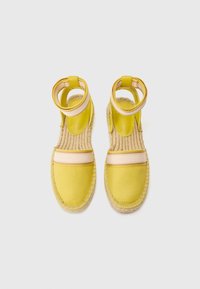 Sandali espadrillas gialli con cinturini alla caviglia, tomaia in tela, suola in corda e una fascia accentata rosa con il nome del marchio.
