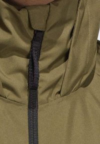 Olivgrön huven jacket med hög krage, justerbar svart snörning och en slät, texturerad yta.
