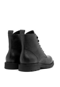 Czarne skórzane botki za kostkę o teksturowanym wykończeniu, okrągłym nosku i kontrastowej czarnej gumowej podeszwie. Posiadają dwa uchwyty oraz sznurowanie z przodu.