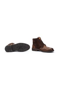 Stivali alla caviglia in pelle marrone e suede con lacci frontali e zip laterale, dotati di suole in gomma testurizzata e cuciture a contrasto.