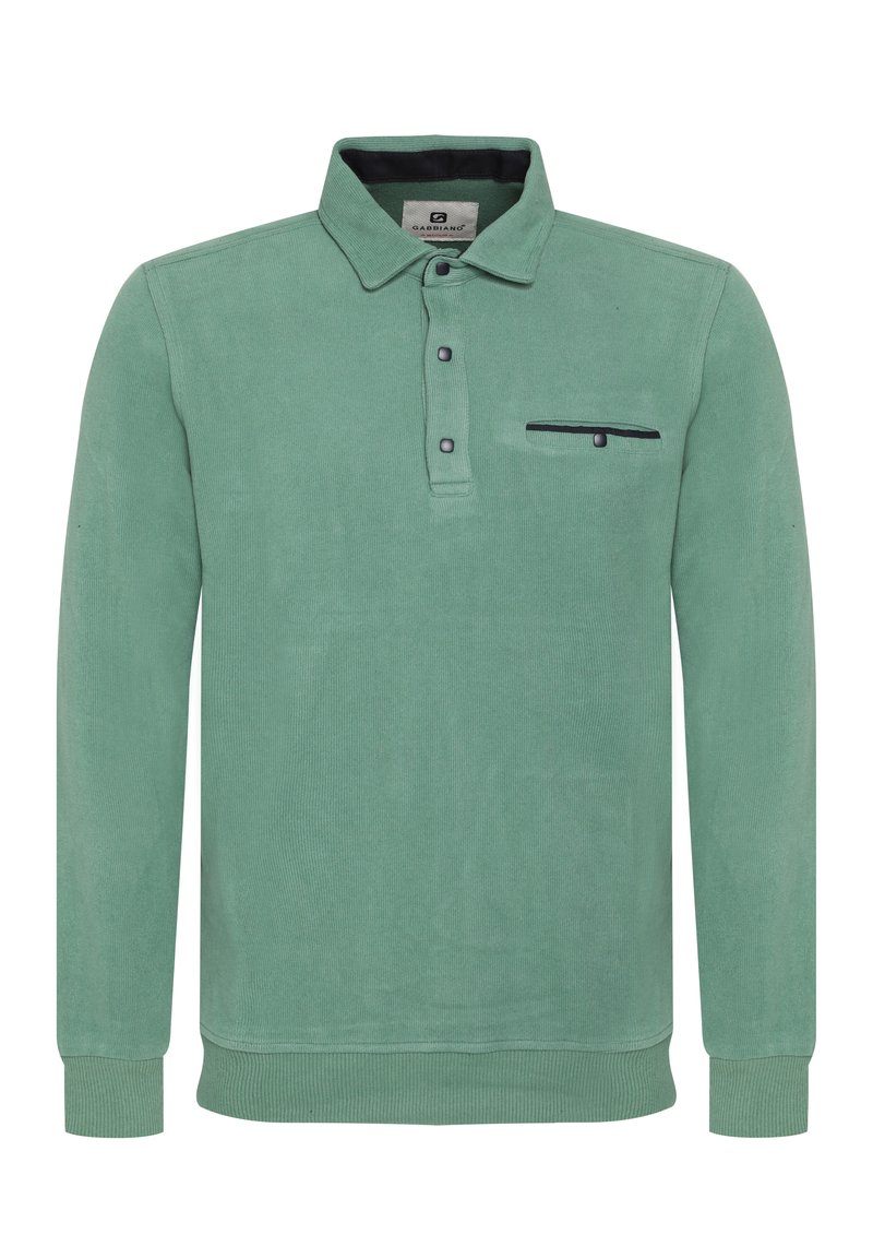 Vihreä puuvillainen pitkähihainen polo, jossa on kauluspaita, kolmesta nappista koostuva napitus ja rintatasku, jossa on musta yksityiskohta.
