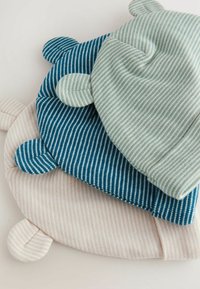 Trois chapeaux doux et rayés dans des tons de rose pâle, vert-bleu et bleu foncé, avec des oreilles arrondies et une forme arrondie, empilés sur un fond clair.