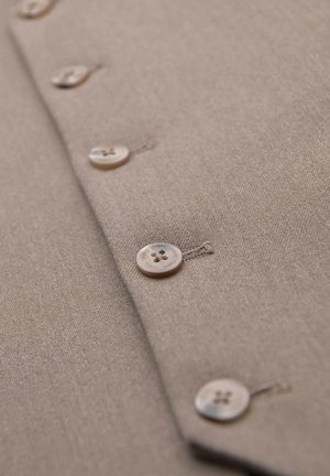 Beige fabric with four visible beige buttons sewn in a vertical line, with the word "OMBRE" engraved on each button.