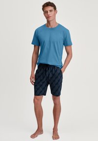 Blauwe T-shirt met korte mouwen, gecombineerd met marineblauwe shorts met een geometrisch patroon. Zachte stof met een ontspannen pasvorm en een trekkoord in de taille.