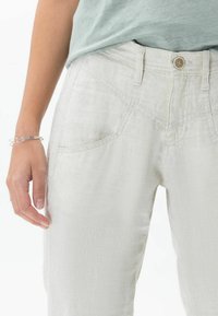 Ljusgrå linnbyxor med en mjuk textur. Funktioner inkluderar framfickor, en enkel knappstängning och bälteshängare.