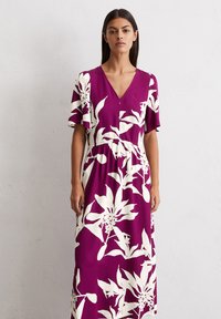 Blumenkleid im Maxi-Style in tiefem Lila mit weißem botanischem Druck. Verfügt über kurze, schwingende Ärmel, einen V-Ausschnitt und einen elastischen Bund für eine perfekte Passform.