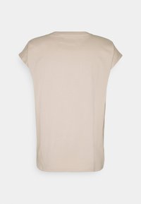 Camiseta de manga corta beige, con cuello redondo, de material de algodón suave, ajuste relajado, diseño sencillo sin patrones ni acentos visibles.