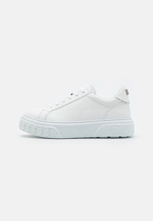 Baltas ādas sporta apavi ar noapaļotu purngalu, izturīgu baltu zoli un paceltu rakstu detaļām uz zoles. Satur smalku logo uz papēža.