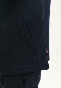 Sudadera de algodón azul marino con un bolsillo lateral, textura suave y una pequeña etiqueta en contraste en el dobladillo. Presenta un corte relajado y un diseño simple.