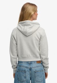 Szara przycięta bluza z kapturem, z prążkowanym wykończeniem na dole i mankietach, zestawiona z wysokim stanem szortami jeansowymi, prezentująca casualowy wygląd.