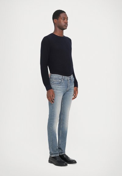 Tengerészeti kötött, hosszú ujjú póló, világoskék, slim-fit farmer és fekete bőrcipő. Egyszerű dizájn, látható minták vagy logók nélkül.