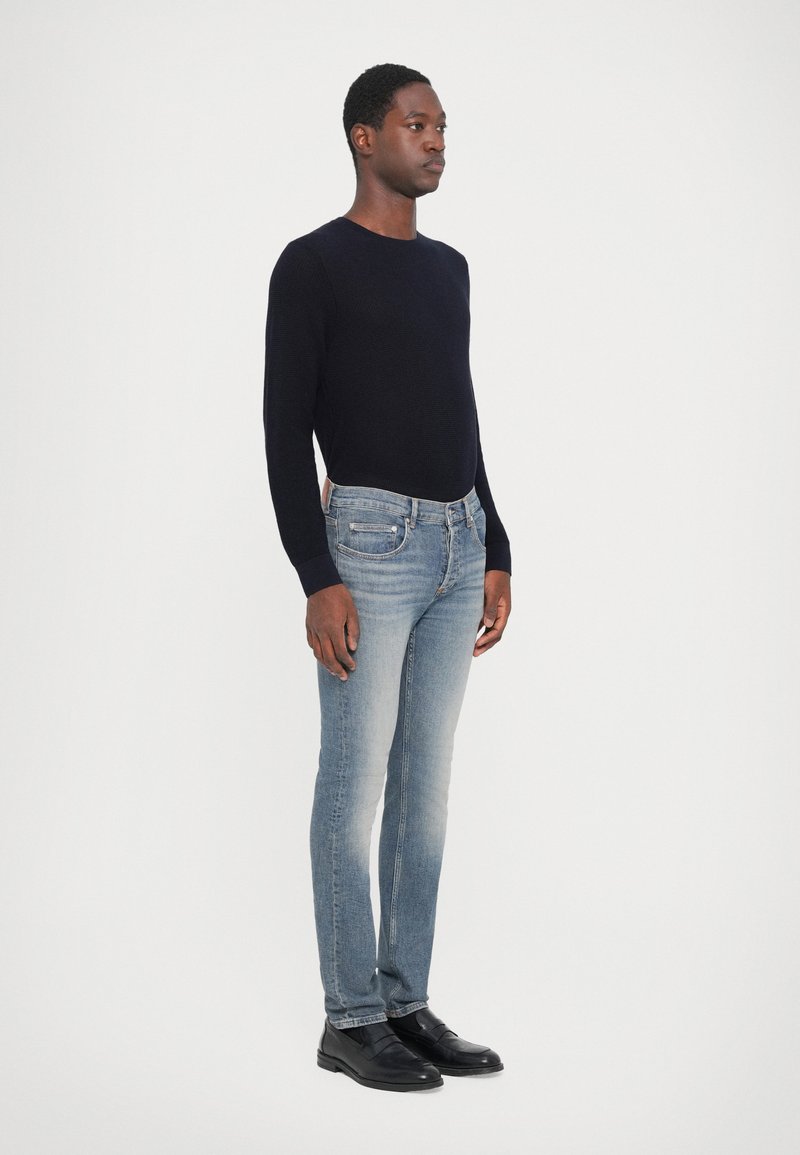 Marine strik langærmet skjorte, lyseblå slim-fit jeans og sorte lædersko. Enkel design uden synlige mønstre eller logoer.