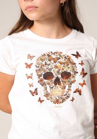 Witte katoenen t-shirt met een schedelontwerp gemaakt van kleurrijke vlinders in tinten oranje en goud. Korte mouwen, basic ronde hals.